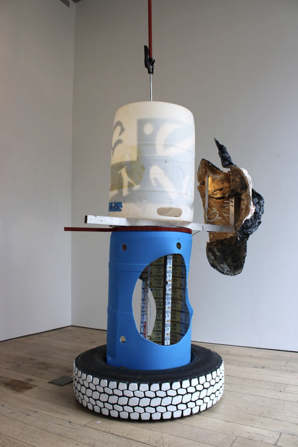 Pooneh Maghazehe Double Barrel, 2024 50 gallon barrel, fiberglass, PlastiDip, FlexSeal, joint compound, tire, latex paint, ceiling jack, aluminum, coupons, flourescent light, plastic lettering, resin, vinyl 48 x 48 x 180 in 121.9 x 121.9 x 457.2 cm