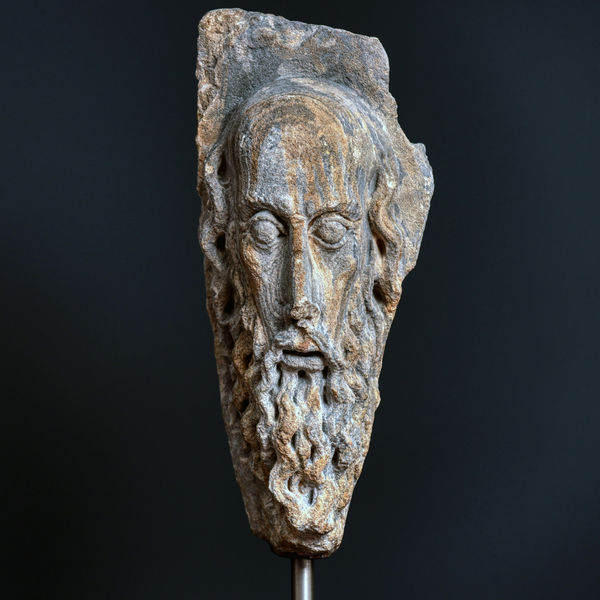 A CARVED STONE HEAD OF A BEARED MAN