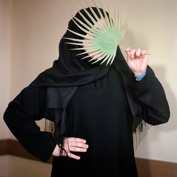 Kevser, who is shy, uses a palm leaf to hide her face at a Quran school, Istanbul, 2017 Archival pigment print mounted on Alu Dibond 19 5/8 x 19 5/8 inches