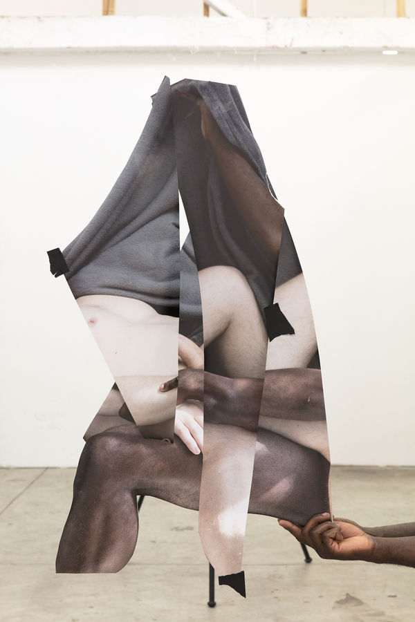 A large roughly triangular collaged view of body parts being held by one visible hand in a photography studio.