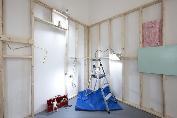 wooden scaffolding on white walls with small dog person statues on a small ladder, on the floor in a red tool box, and sitting and smoking a cigarette at Stephen Morrison Dog Show #4: House Broken exhibit