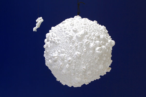 Floating moon composed of molds of lips with floating figure of astronaut composed of casts of fingers.