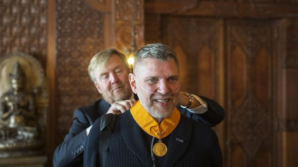 the King of The Netherlands places Medal of Honor around the neck of artist Erwin Olaf