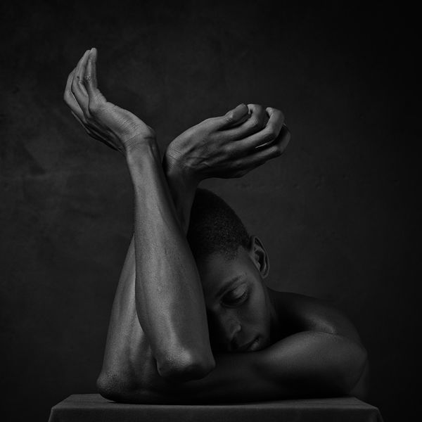 black man with arms crossed lyrically against black background by Erwin Olaf