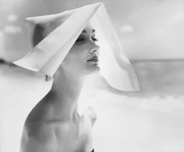 Lillian Bassman black-and-white photograph of woman in white starched hat on beach