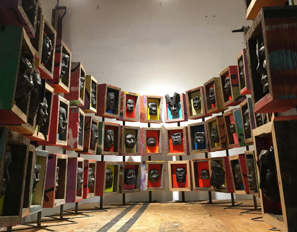 Harlan Mack Future Kin, 2016 - 17 50 forged steel faces, reclaimed wooden fence, reclaimed plywood, and acrylic paint dimensions variable