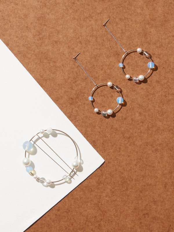 Left: Mariko Mori, Planets Earrings, 2013, 18k white gold, Akoya pearls, vaseline glass bead, aurora bead and crystal bead; Length: 9.0 cm, diameter: 4.0 cm (each), 13g (per pair), edition of 10 in collaboration with Louisa Guinness. Right: Mariko Mori, Planets Brooch, 2013, 18k white gold, South Sea pearls, Akoya pearls, broken glass bead, aurora bead and crystal with pins on reverse; Diameter: 7.0 cm, 20g, incised with artist’s signature and hallmarked, edition of 10 in collaboration with Louisa Guinness.