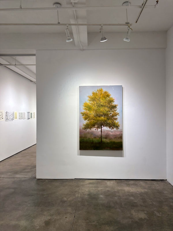 Photo of an installation with one painting visible. It is of a tree, framed symmetrically in the center of the canvas.