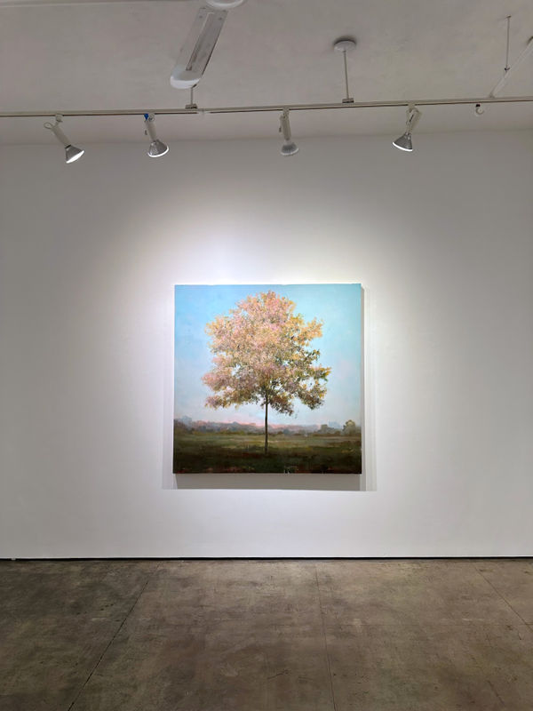 Photo of an installation with one painting visible. It is of a tree, framed symmetrically in the center of the canvas.