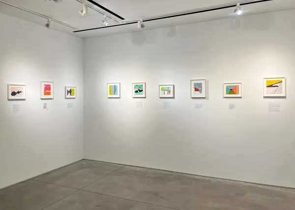Small colorful paintings hung on a gallery wall.