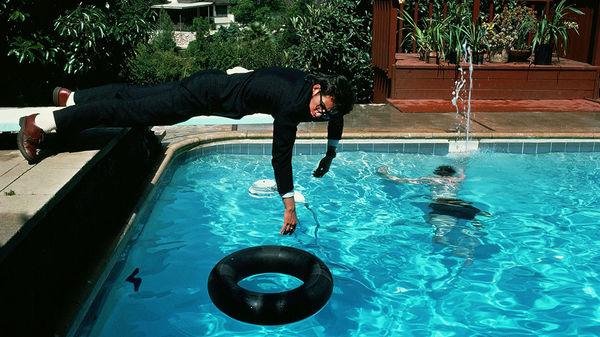 Elvis Costello laying on the plank, board for jumping above the swimming pool, Brian Griffin, laying on plank in suit, blue water, surreal, drunk, after party, signed print, mmx gallery, Elvis Costello And The Attractions, Club Tropicana, Los Angeles, LA,
