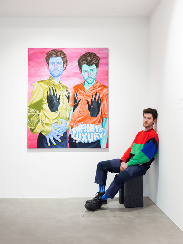 Damien Cifelli, sitting next to his painting Infinite Luxury, 2023, at PULPO GALLERY on the occasion of his exhibition The Thing Beyond: Adventures in Tarogramma at PULPO GALLERY