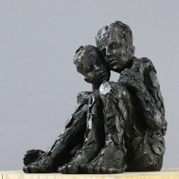 Carol Peace sculpture of a couple, sat side by side, embracing, with their heads close together. The surface is a rough texture and the colour is dark almost black.