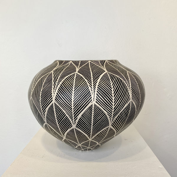Ant & Di Edmonds - Tydd Pottery wide, heart shaped ceramic black and white vessel with a vertical zig zag pattern. wide, round ceramic pot, slightly V-shaped, decorated in a black and white leaf shape pattern