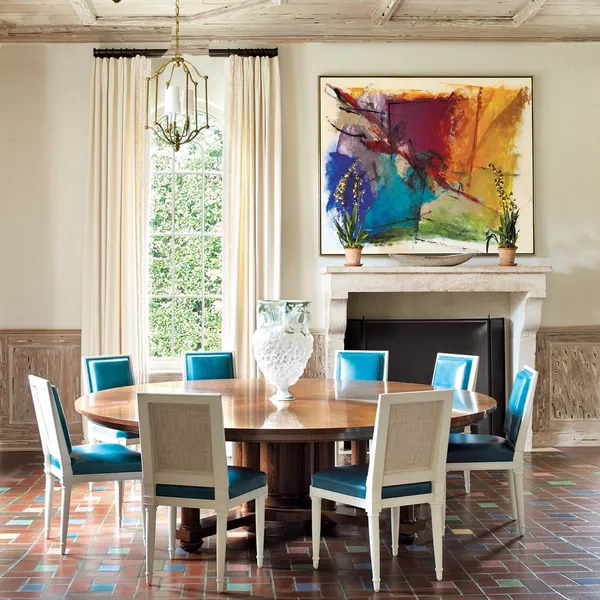 The shade of turquoise custom-dyed for the Moore & Giles leather on the Van Day Truex dining chairs came from the color of the home's original cabochon tiles. The polished-oak table by David Kleinberg Design Associates brings warmth to the space. The artw