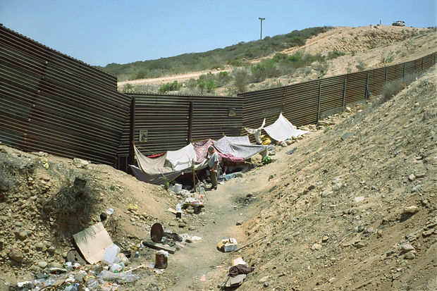 While I park the bike, I notice the migrants bringing my bag with the Leica, large-format and video cameras, the...