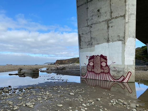 Photo of underpass on a beach near the ocean with GATS graffiti on it