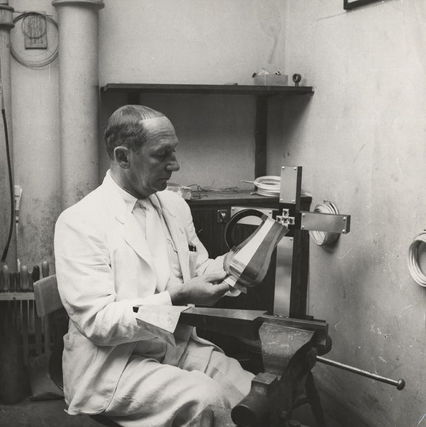 Wiwen Nilsson in his workshop holding a water jug. Pictured behind, an altar cross in silver, rock crystal, and ebony made in 1950.