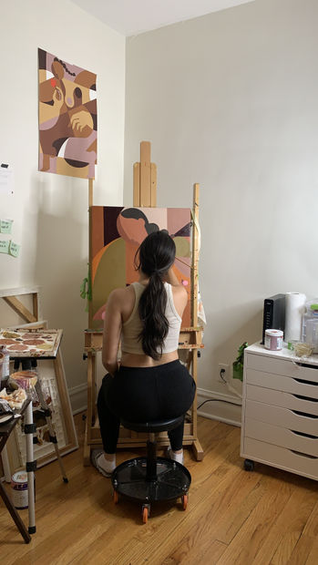 Artist Liz Flores in her studio painting a canvas for her exhibition