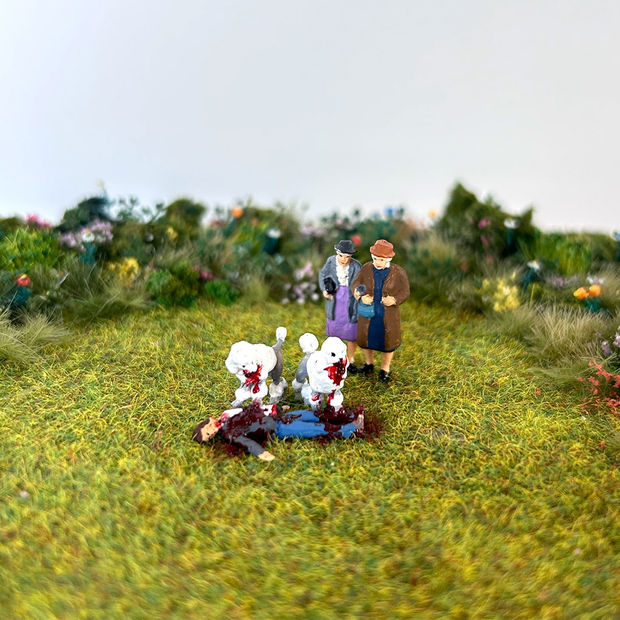 Photo of a miniature sculpture of two poodles attacking someone while two people watch