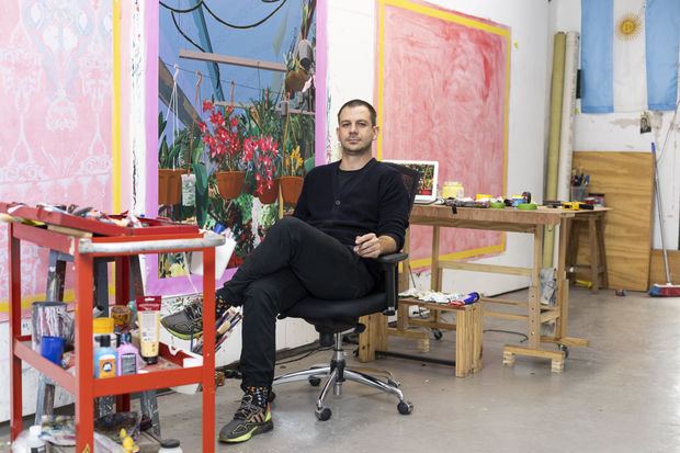 Artist Francisco Diaz Scotto in his studio sitting in front of his paintings