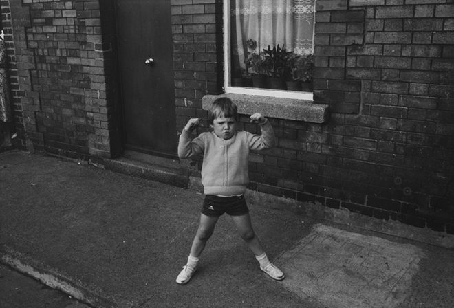 Jill Freedman, Untitled [Young Irish boy flexing his muscles], circa 1985
