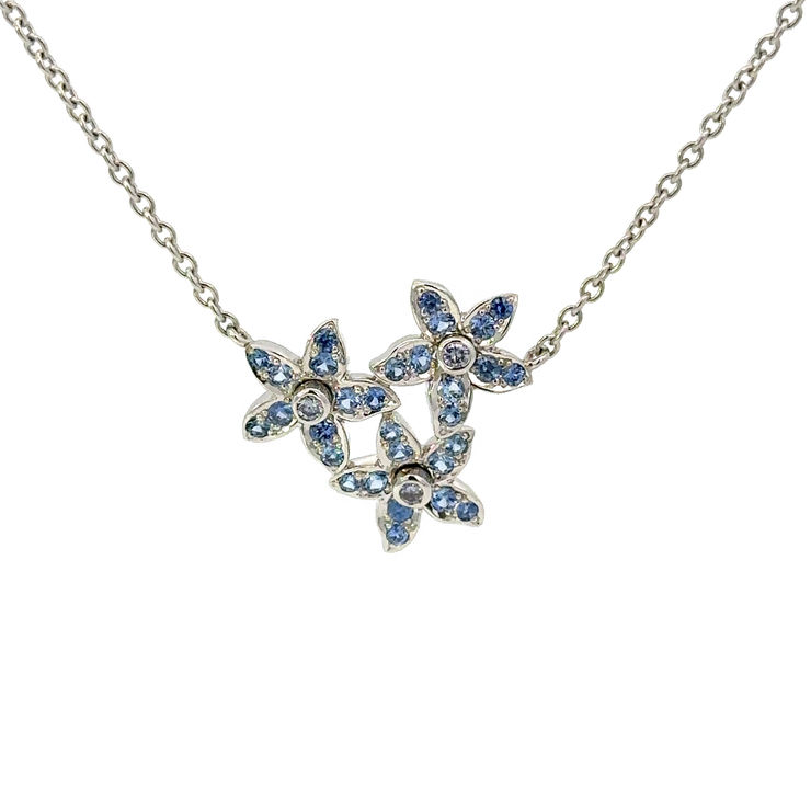 Bespoke Aril Jewels delphinium pendant featuring natural blue diamonds & unheated cornflower blue sapphires in platinum. Pictured on white background.