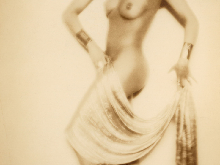 A nude Josephine Baker strikes an artful geometric pose while holding a swath of fabric draped over her leg.