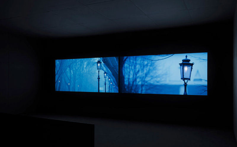 2 projection screens sit horizontally in a dark theater, both display street lamps in front of an aqua sky. 