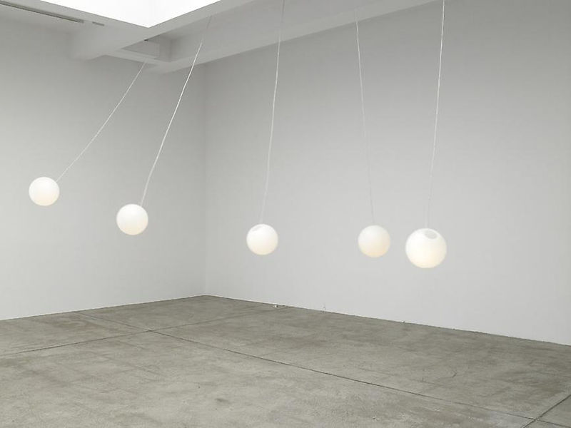5 white balls hang from the ceiling in a white room. 