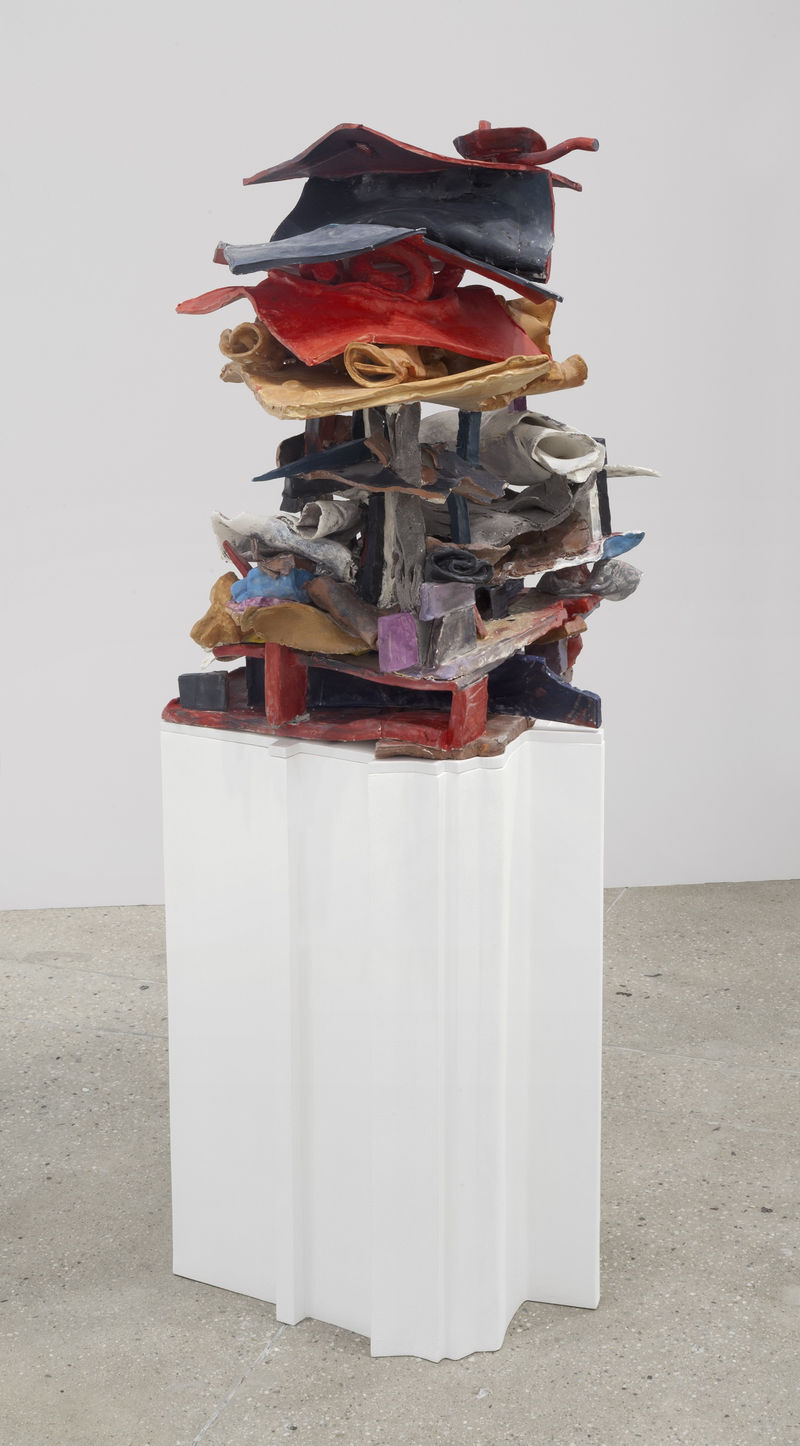 An abstract sculpture sits on a white pedestal.