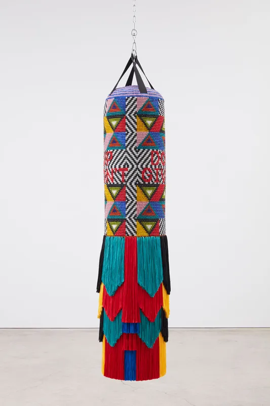 Jeffrey Gibson DON'T GIVE UP, 2023 Repurposed punching bag, acrylic felt, glass beads, artificial sinew, and nylon fringe 74 x 18 1/2 x 18 1/2 inches 188 x 47 x 47 cm 55.0 lbs.