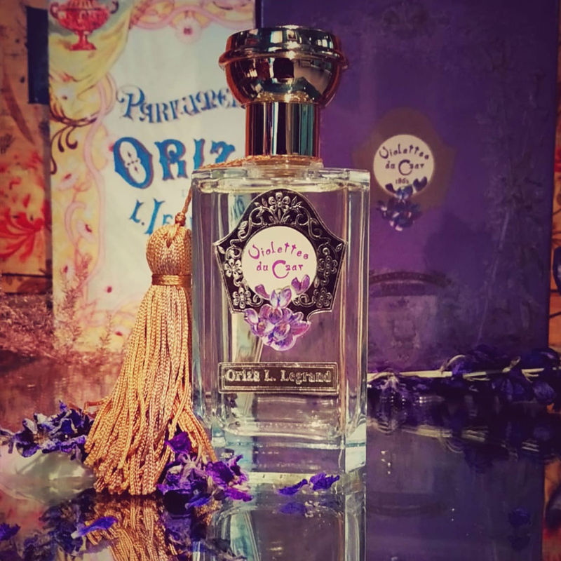 A perfume bottle VIOLETTES DU CZAR by Oriza L. Legrand standing on a mirror with packaging on the background