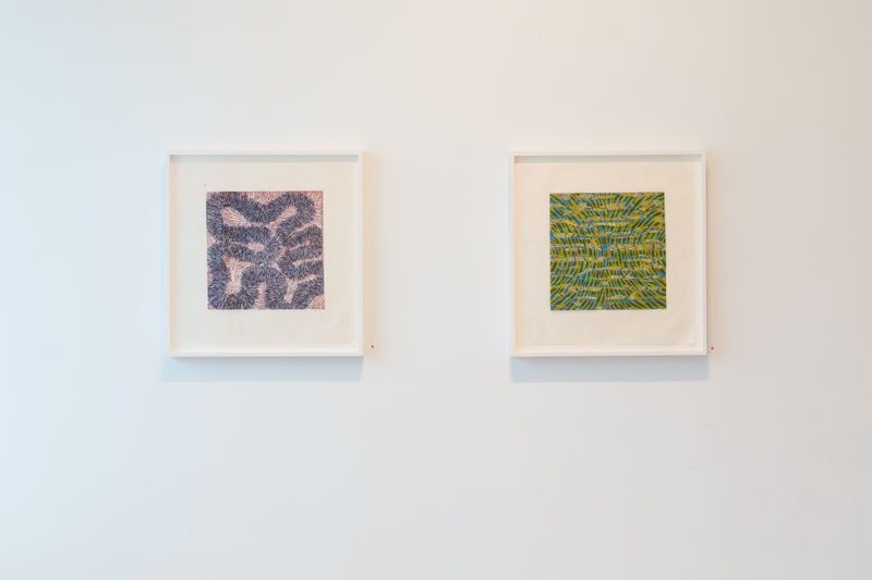 Two colorful abstracted Sue Heatley works on paper shown on the same wall, the one on the left purple and pink, the other predominantly green and dense.