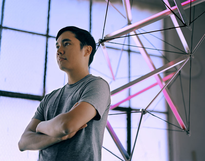 Photograph of James Clar standing in front of one of his light based works.