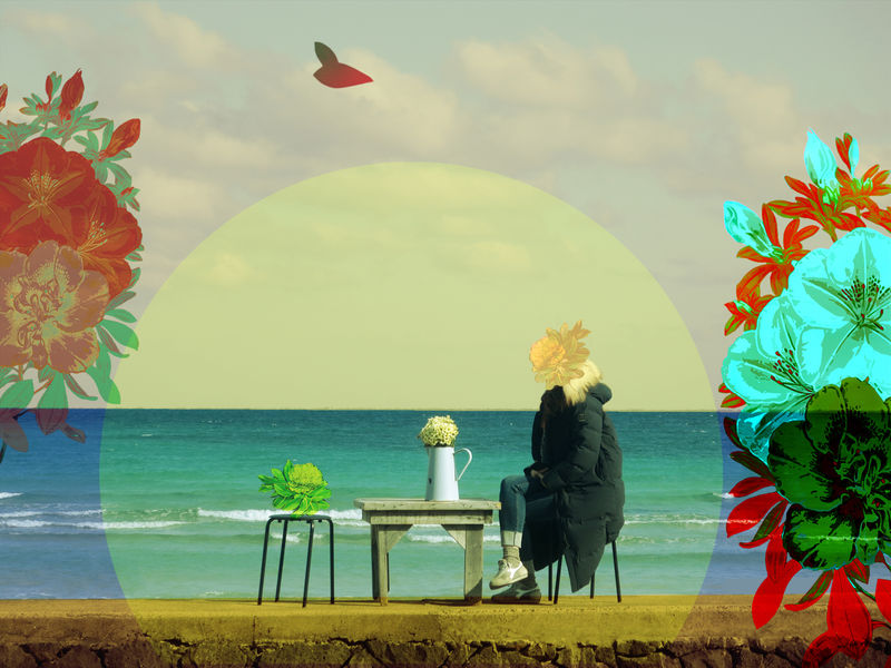 women on beach with coat on and flower over her head and other flowers