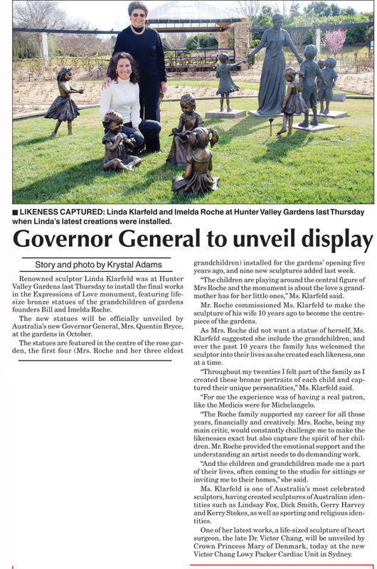 Linda Klarfeld and Imelda Roche are pictured together at Hunter Valley Gardens, surrounded by bronze statues of children from the Expressions of Love monument. Linda kneels beside a sculpture of a child, while Imelda stands behind her, smiling. The sculpt