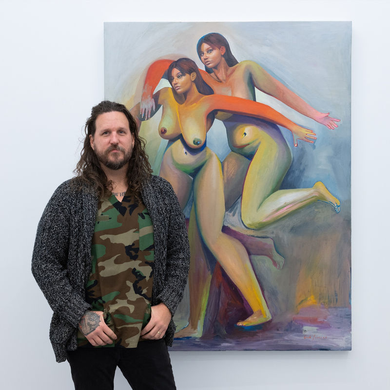 portrait of artist Erik Jones in front of painting three nude figures with the same face and colorful bodies