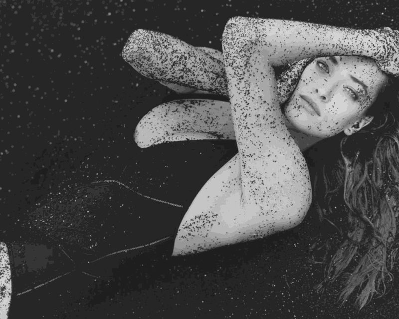 Herb Ritts photograph of Tatjana in bathing suit reclining in black sand, Hawaii