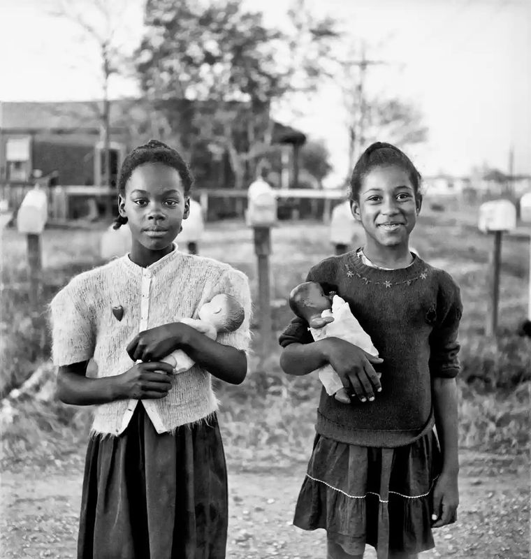 Elliott Erwitt photograph of two girls holding dolls looking at camera