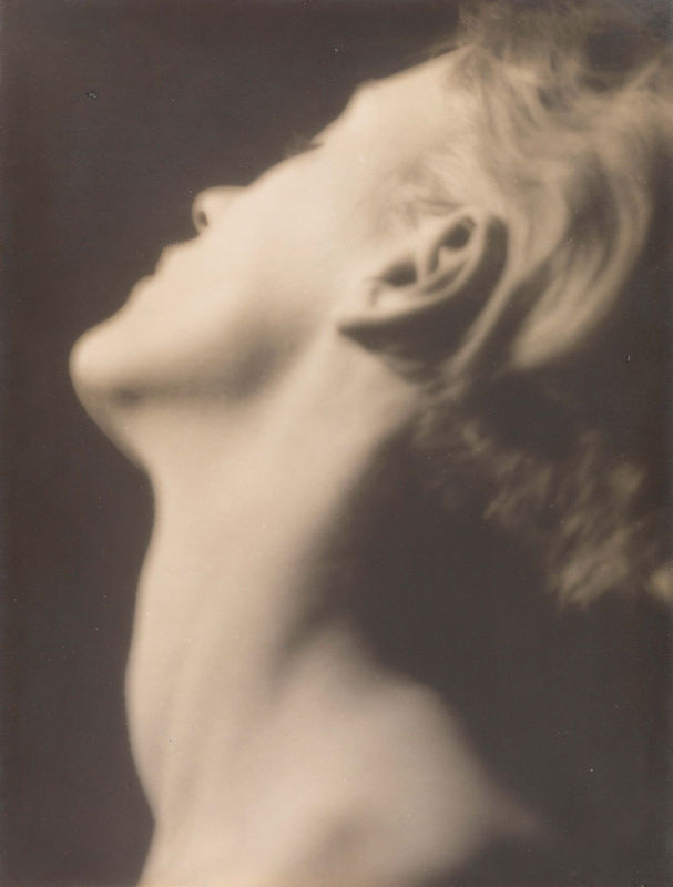 Soft-focus black-and-white photograph by Man Ray showing Lee Miller in profile with her head tilted back, emphasizing the graceful curve of her neck and jawline.