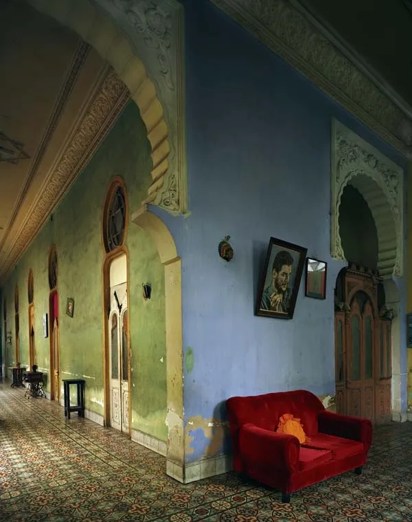Michael Eastman photograph of a Havana interior with arched doorways, patterned tile floor, peeling walls, and a red sofa beneath a portrait.
