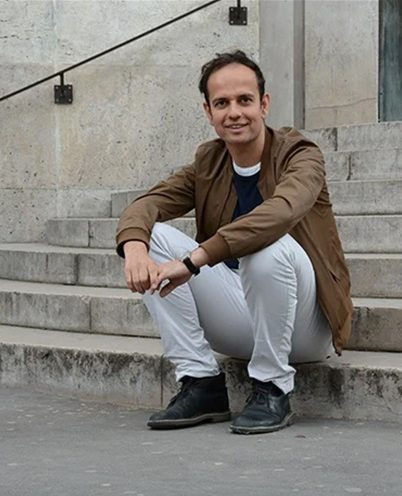 Portrait of Tino Sehgal sitting on an outdoor staircase. 
