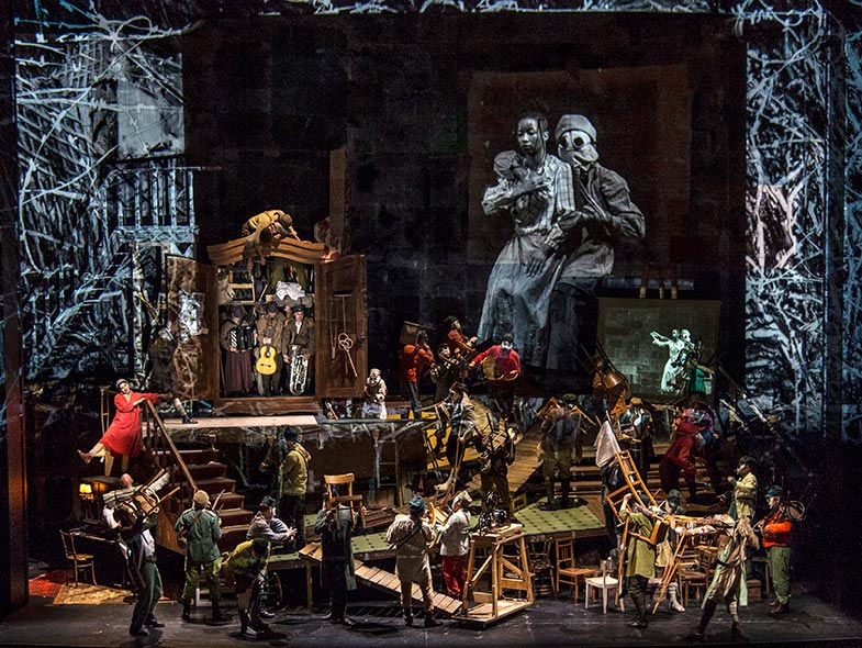 An elaborate stage-set with multiple actors interacting with props and instruments. 