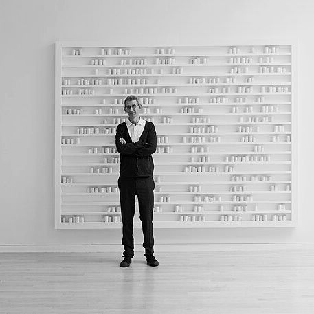 The artist, Edmund de Waal, stands in front of his installation of ceramic vessels, breathturn (2013), at Gagosian Gallery in New York