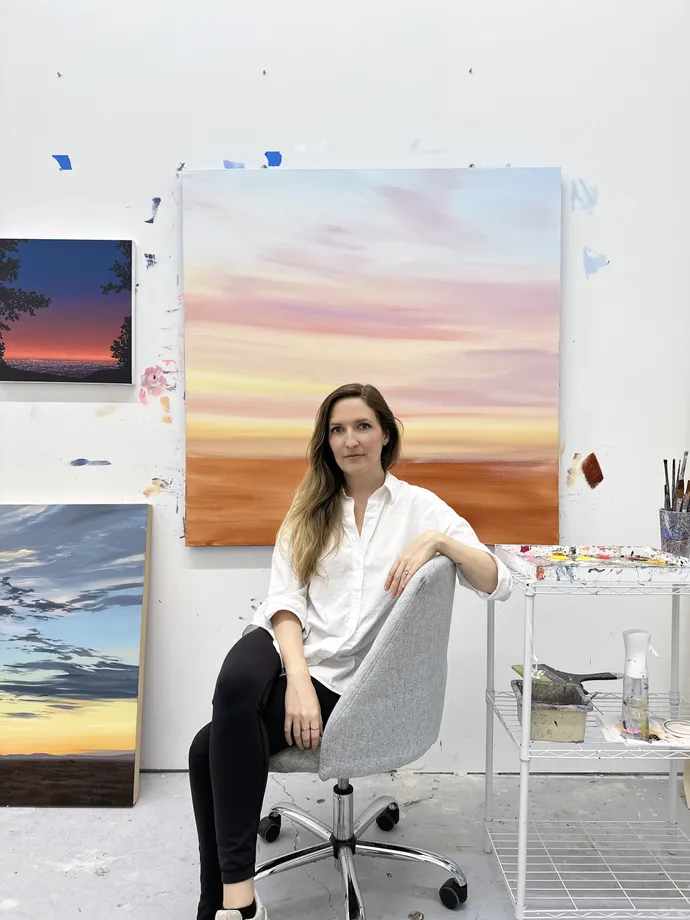 Artist Kristin Moore in her studio with original paintings